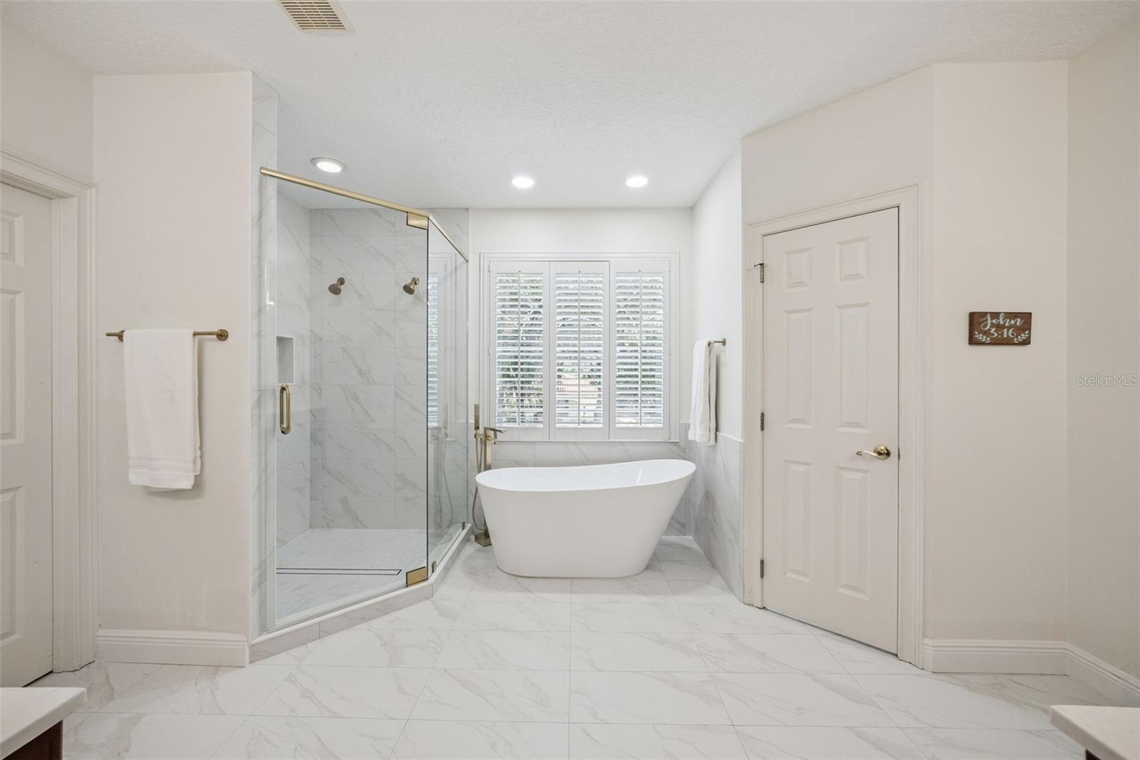 Beautiful newly renovated primary suite with glass shower doors, soaking tub, private water closet and walk in updated closet