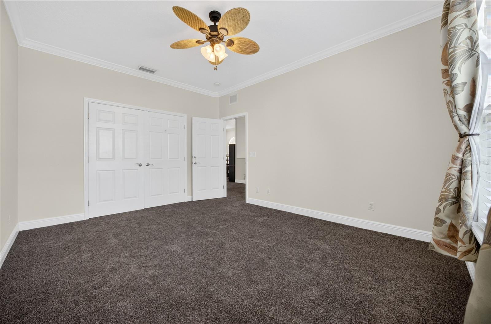 Bedroom across from the stairs with ceiling fan and double closet