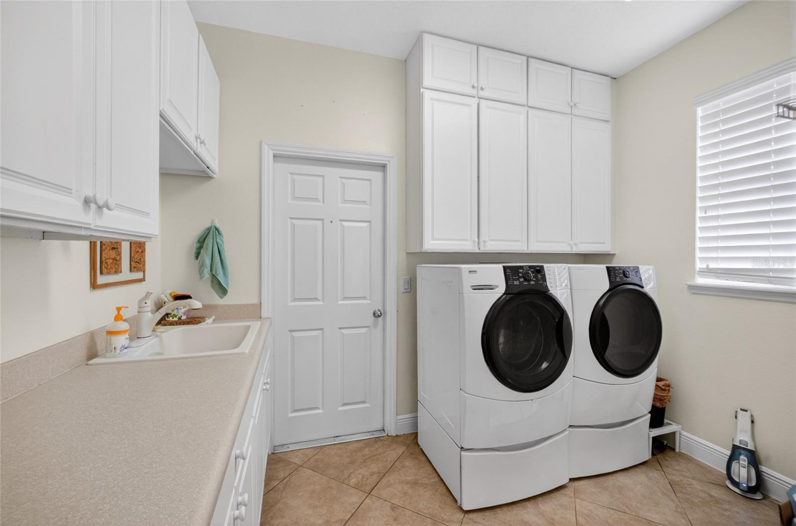 First flr laundry room. Washer and dryer remain. Built in white cabinets for storage.