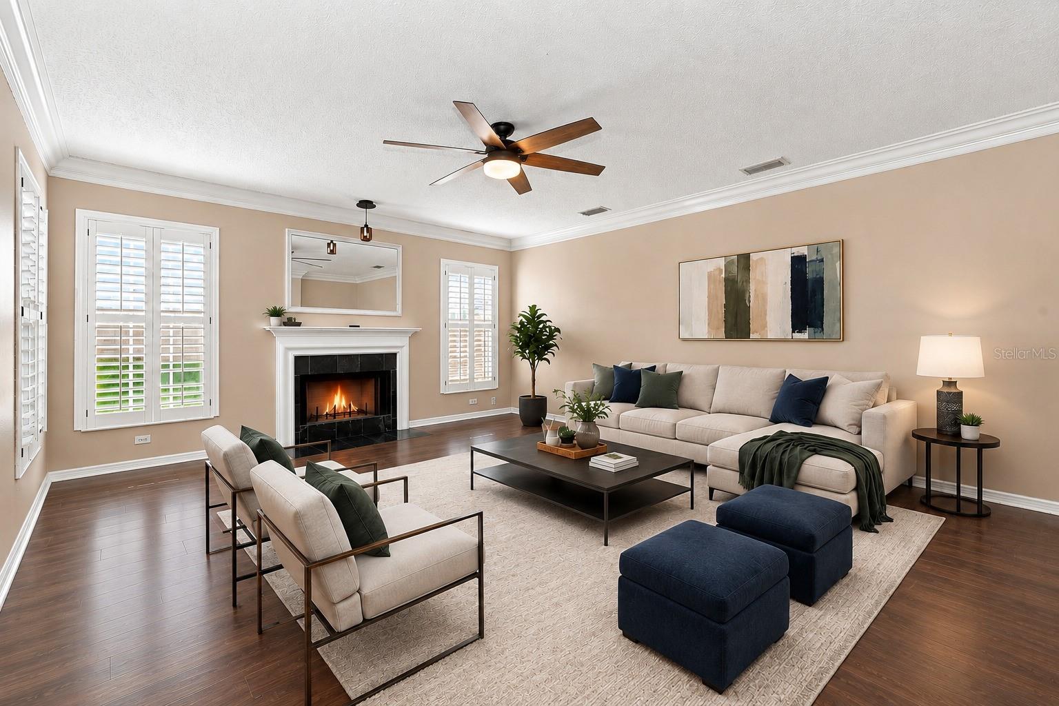 Spacious Formal Living Room featuring BRAND NEW LVP flooring, crown molding, plantation shutters, and a cozy wood-burning fireplace.