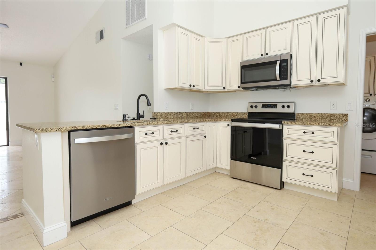 Spacious kitchen with travertine tile flooring, granite countertops and stainless steel appliances.
