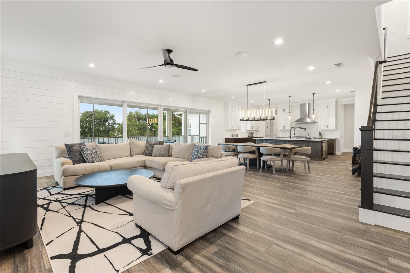 LIVE, DINE, SOCIAL Extends toward the kitchen and expansive sliding glass doors, bringing the screened porch and conservation landscape into view.