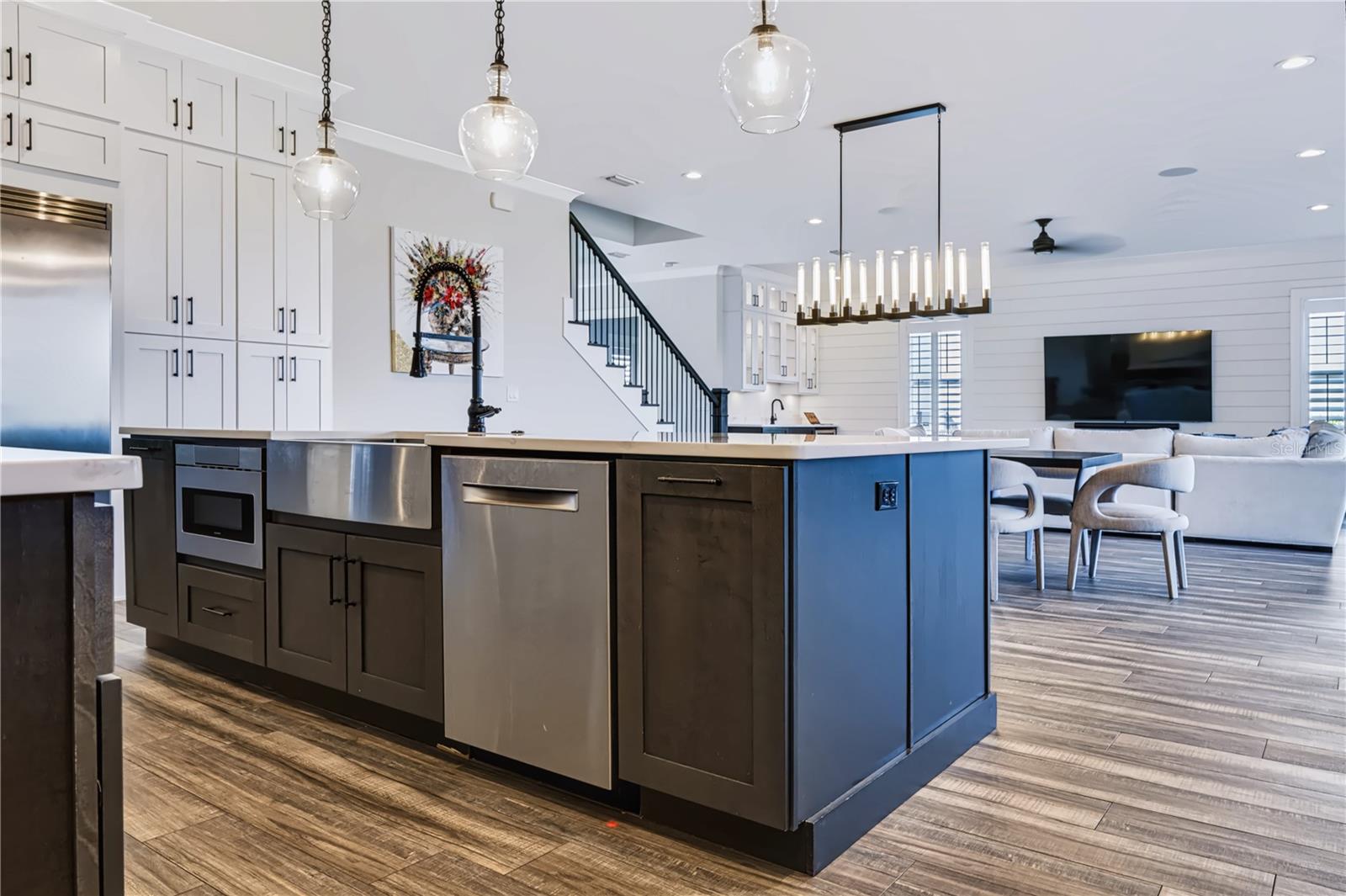 OVERSIZED CENTER ISLANDThe oversized center island incorporates an apron-front sink, dishwasher and under-counter microwave, with generous prep space and an open connection to the dining and living areas beyond.