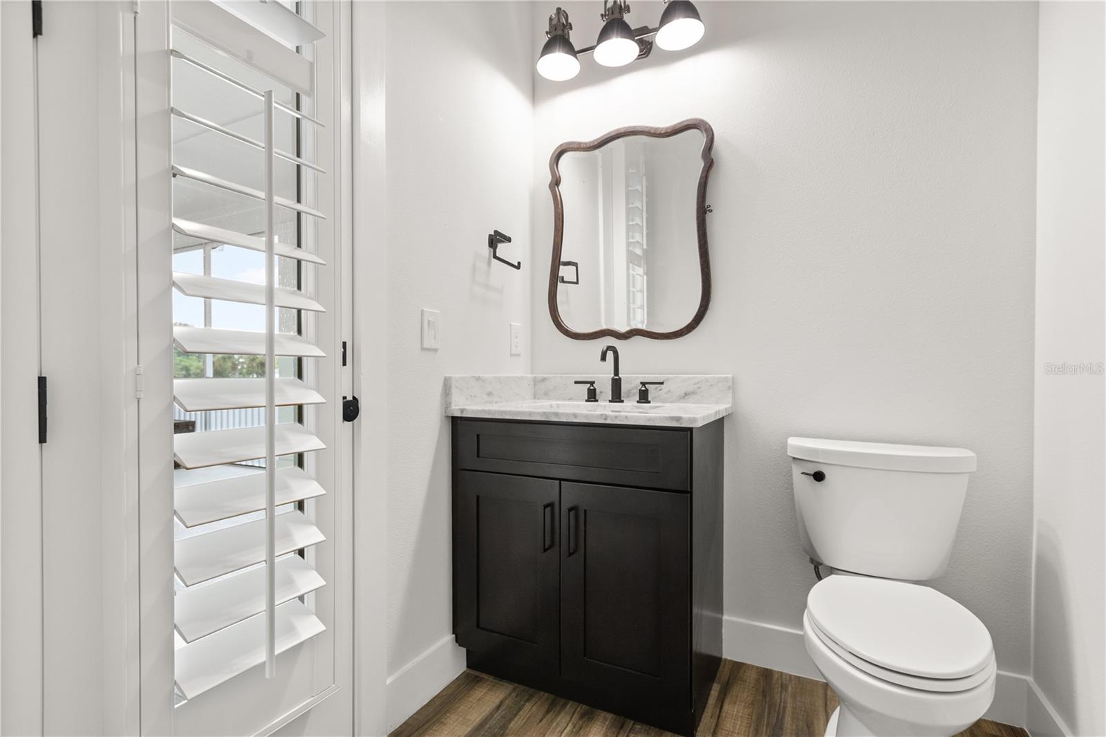 1/2 BATH + SCREENED PORCH ACCESSConveniently located just off the kitchen, this 1/2 bath provides direct access to the screened porch and sits just before the private primary wing