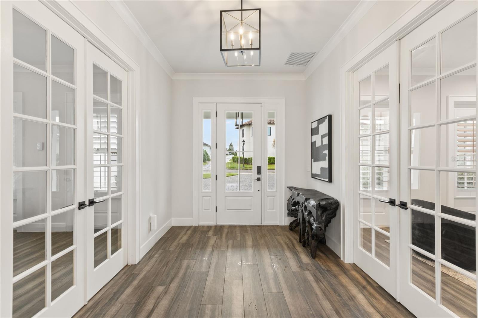 TWO PRIVATE ROOMS OFF THE FOYER Looking toward the front entry, the foyer is framed by double French doors leading to a dedicated executive office on one side and a flexible en suite guest or au pair room on the other