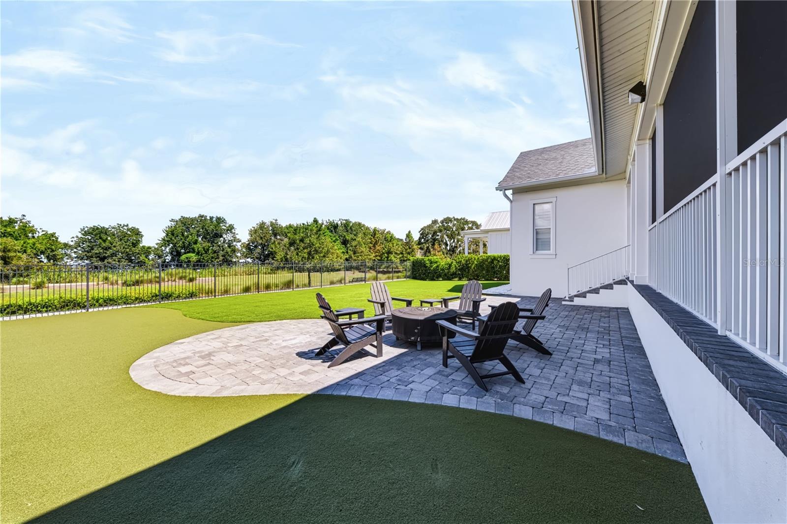 PAVER PATIO A spacious paver patio creates a separate gathering area within the backyard, framed by the open conservation setting beyond the fence.