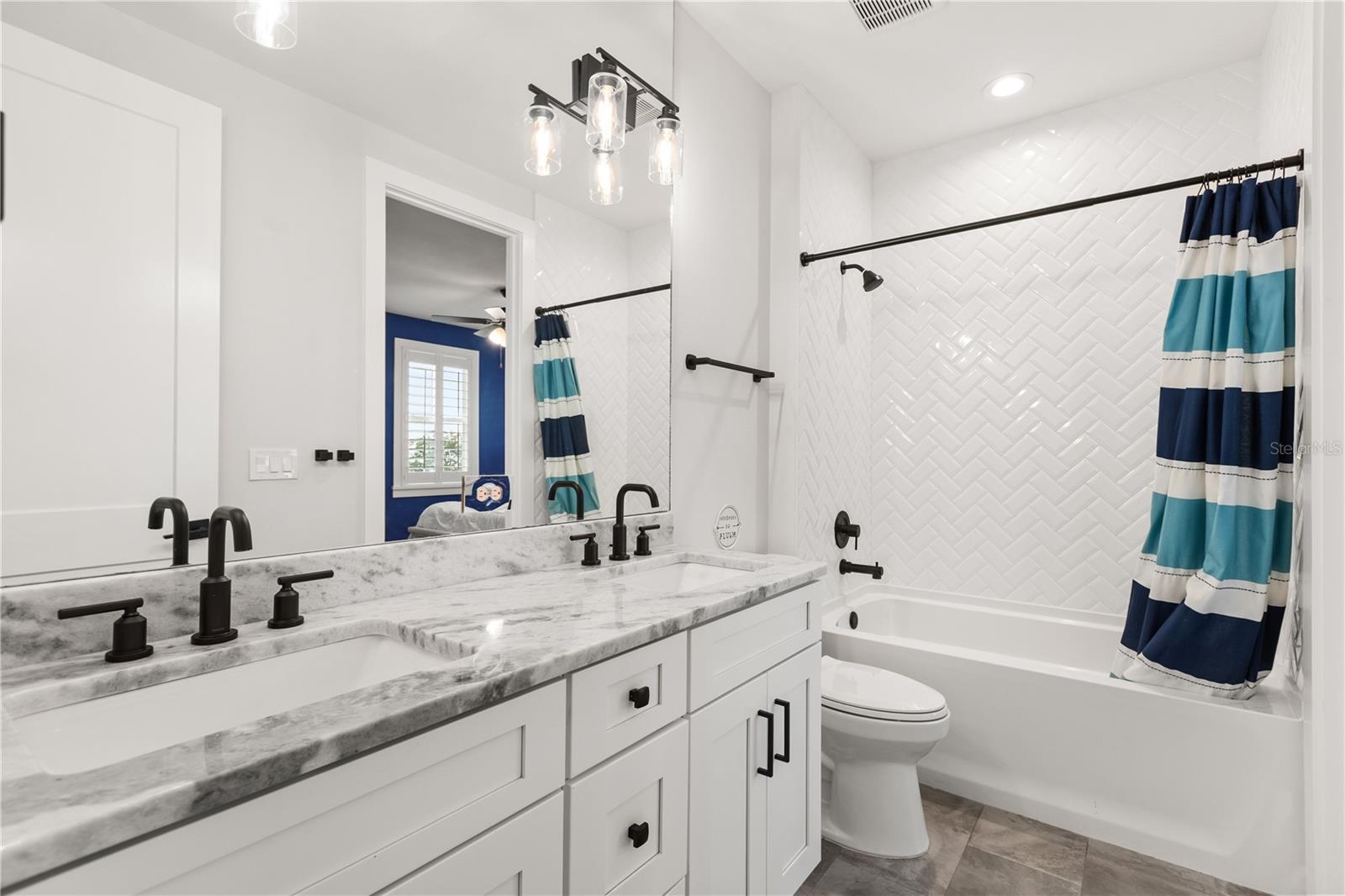 JACK & JILL FULL BATHShared between the two rear bedrooms, the Jack & Jill bath features dual sinks and a tub-and-shower combination with herringbone tile surround.