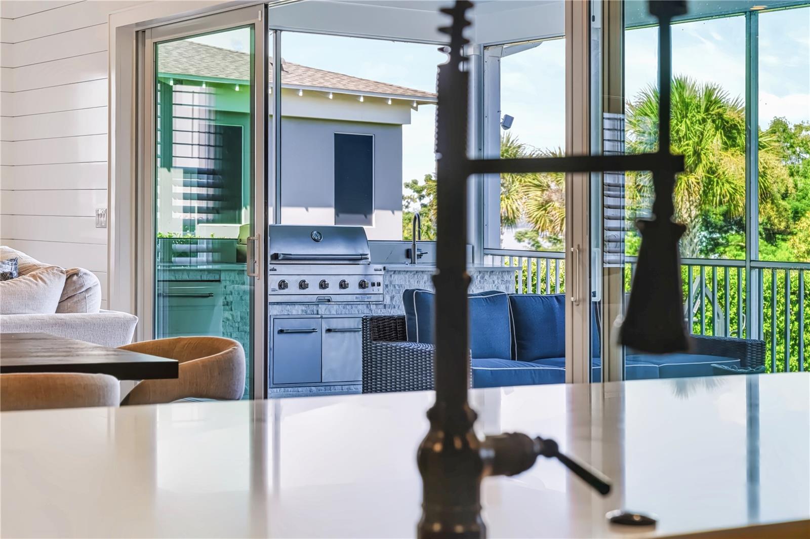 KITCHEN TO OUTDOOR KITCHENThe kitchens oversized island sits within direct sight of the screened porch and outdoor kitchen, creating an easy connection between indoor cooking and outdoor entertaining.