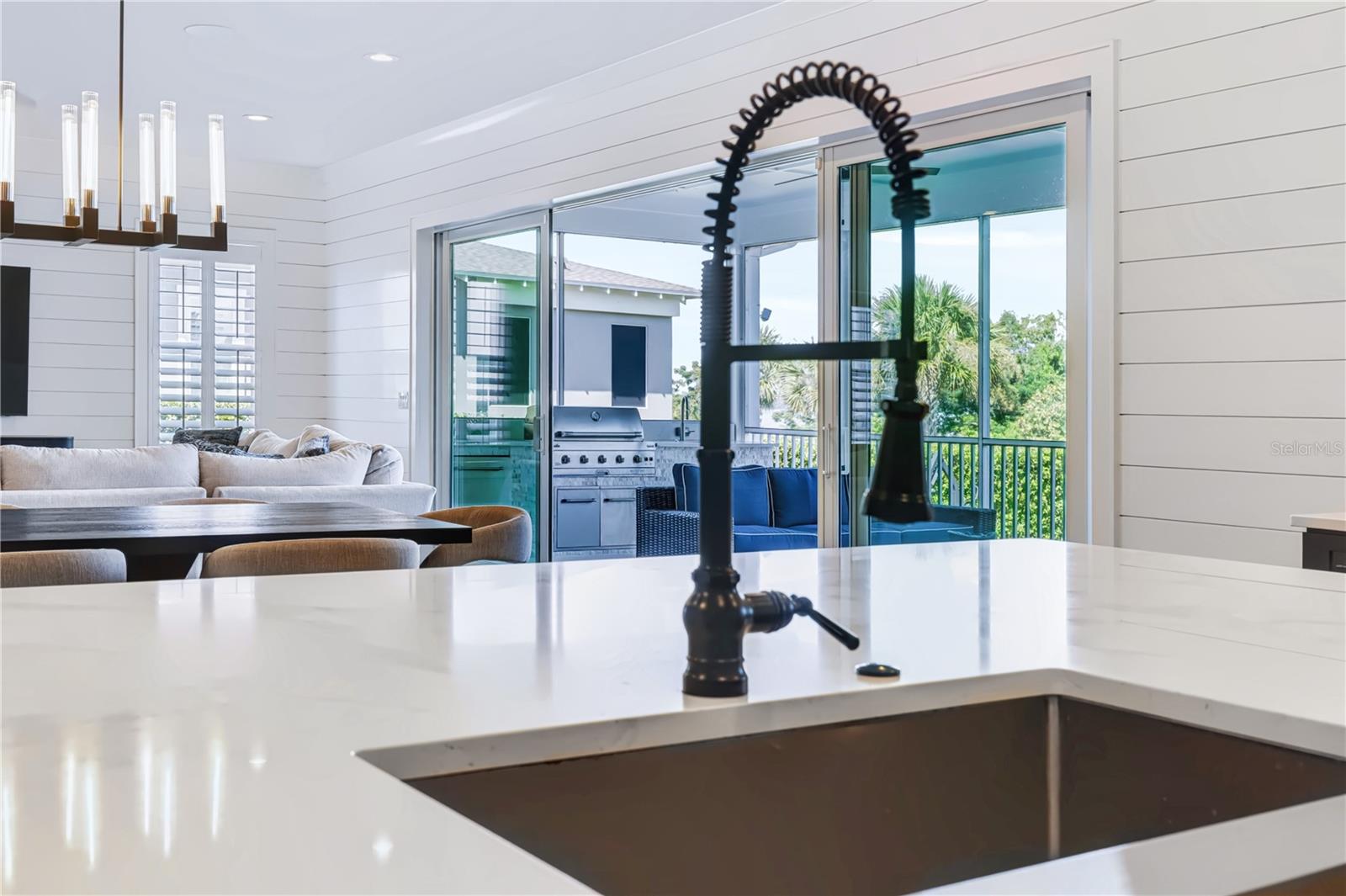 INDOOR-OUTDOOR LIVINGFrom the kitchen island, the open living and dining spaces lead directly through expansive sliding glass doors to the screened porch and outdoor kitchen.