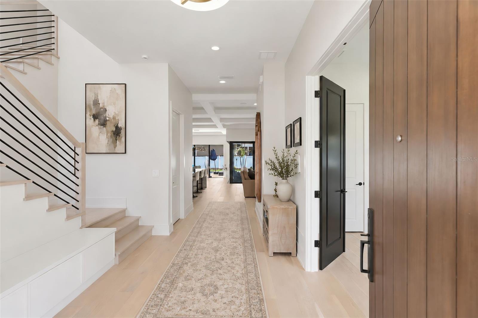 Entryway into the home with built in storage bench to the left and guest bedroom with double doors to the right Entryway into the home with built in storage bench to the left and guest bedroom with double doors to the right