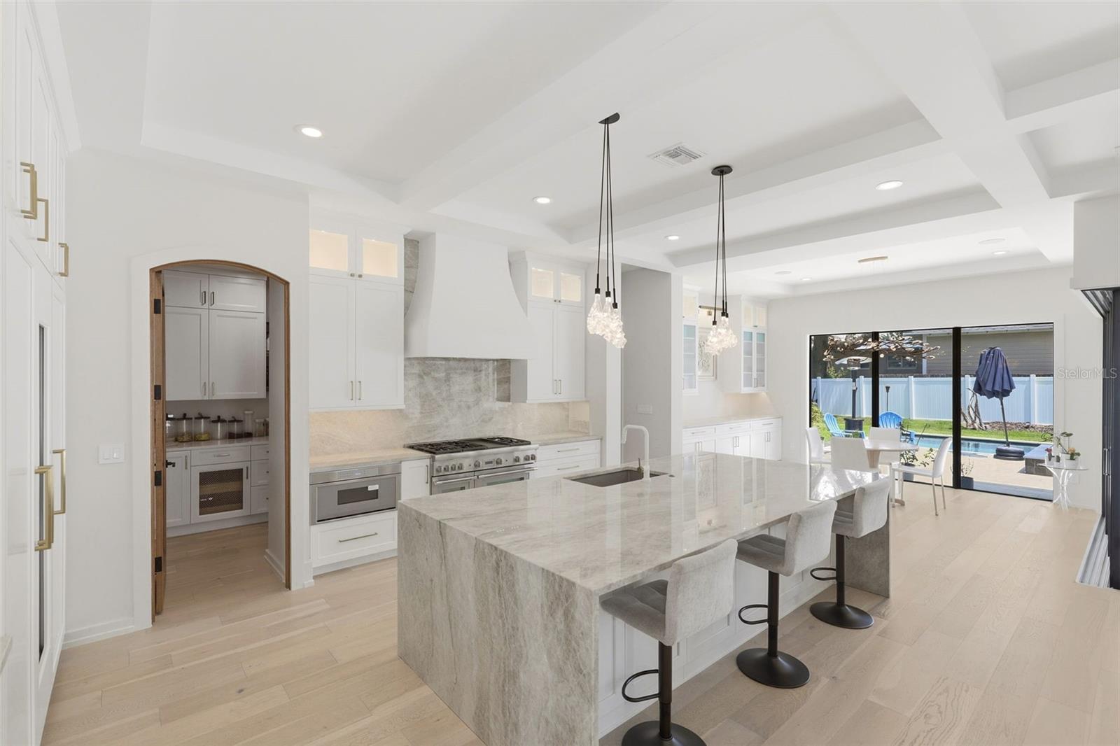 Kitchen features crystallized quartzite counters, oversized waterfall island & walk-in panty Kitchen features crystallized quartzite counters, oversized waterfall island & walk-in panty