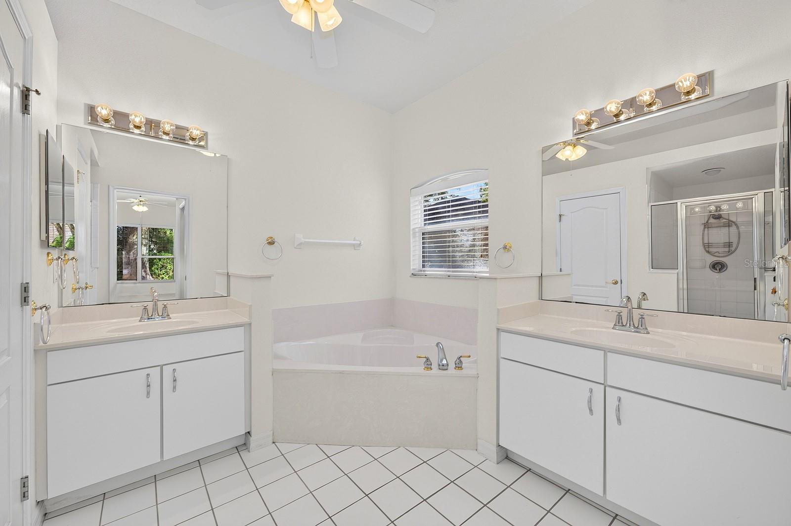 The PRIVATE EN SUITE BATH features dual vanities, a relaxing garden tub, a separate step-in shower with a NEWER LIGHT (2023), and a private water closet.