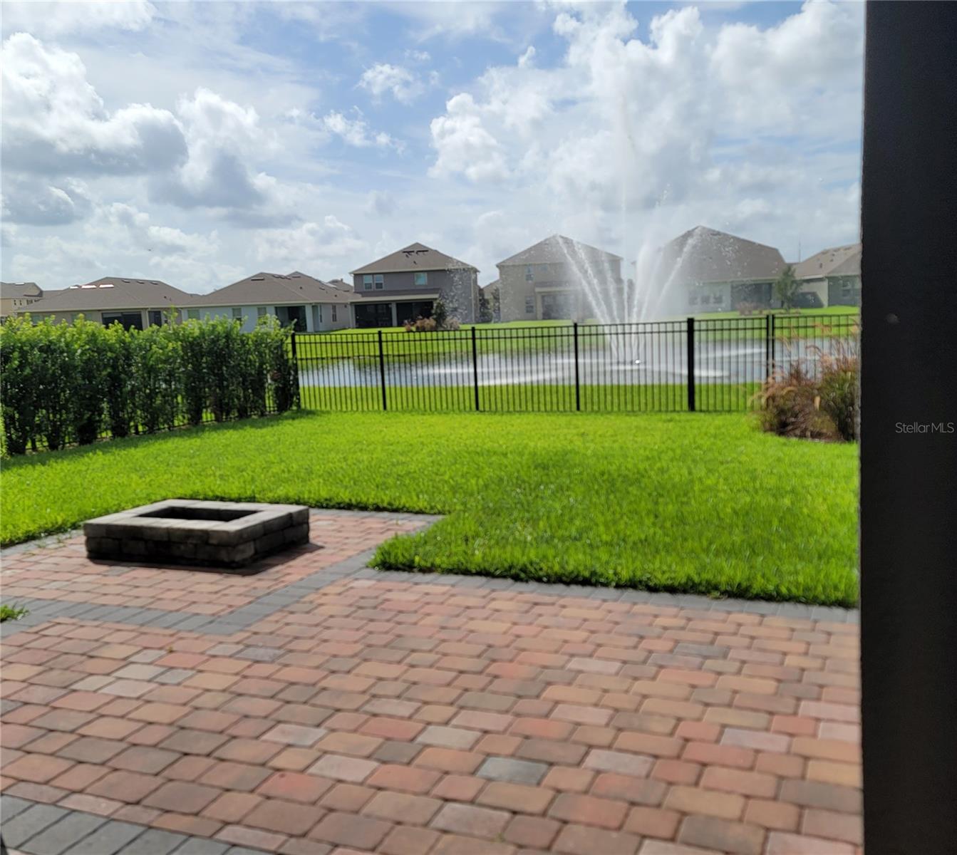 Private Fenced Yard with extended pavers, firepit, privacy bushes, and water view overlooking beautiful fountain
