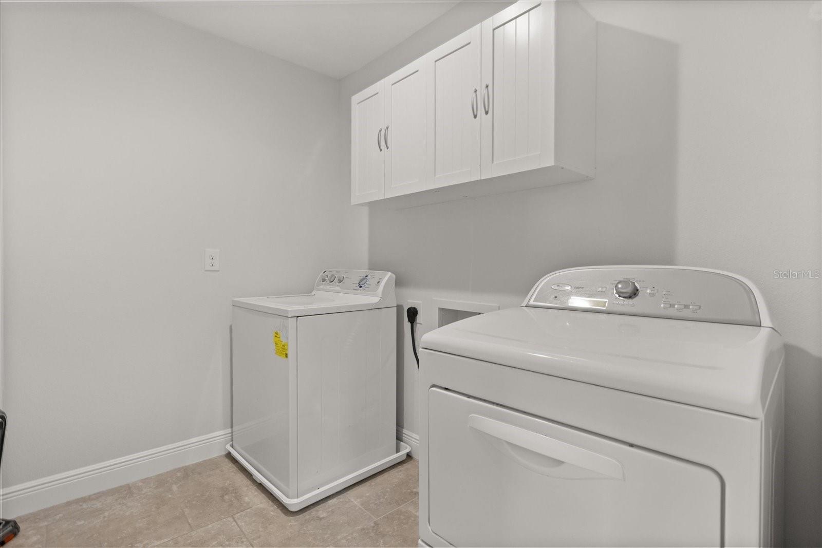 Nice size laundry room upstairs near bedrooms with added cabinets for storage