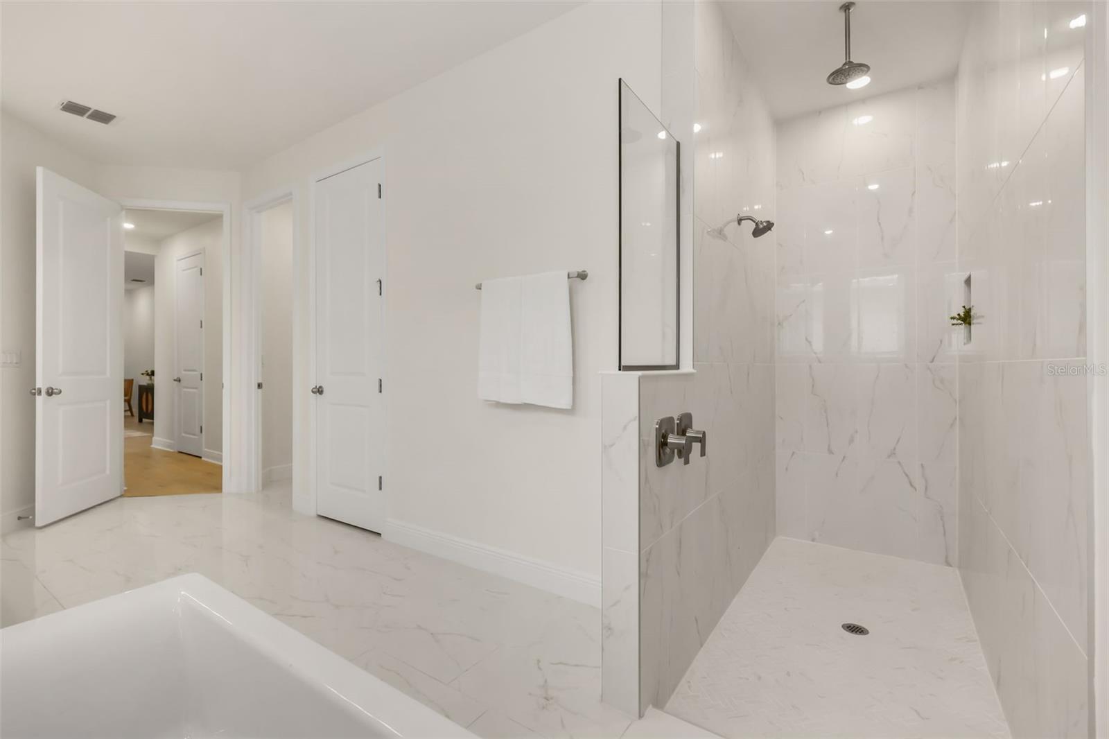 Luxurious primary bathroom with shower, dual vanity, soaker tub, and water closet