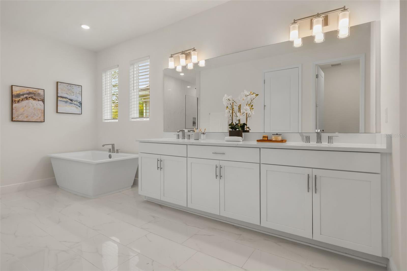 Luxurious primary bathroom with shower, dual vanity, soaker tub, and water closet