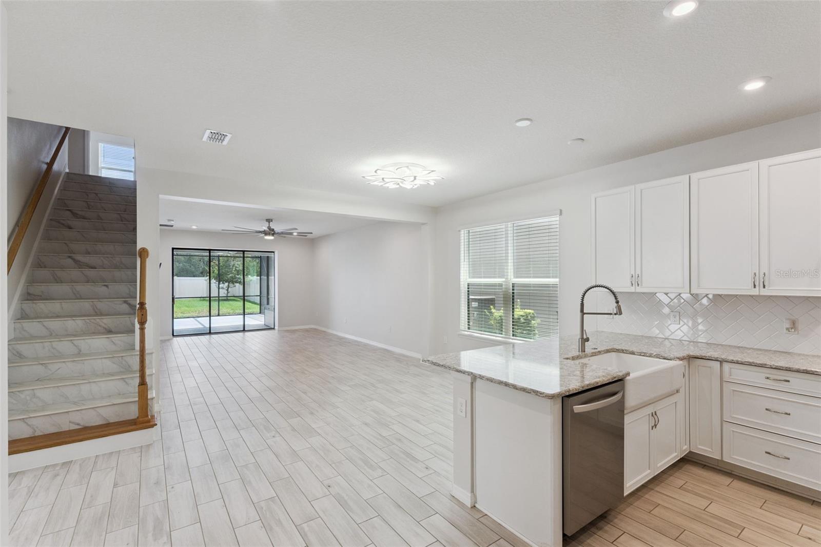 Kitchen & Main Living Area  Wide view highlights the home's open layout, with the kitchen flowing into the spacious living area and sliding glass doors extending the sightline to the screened patio and backyard.