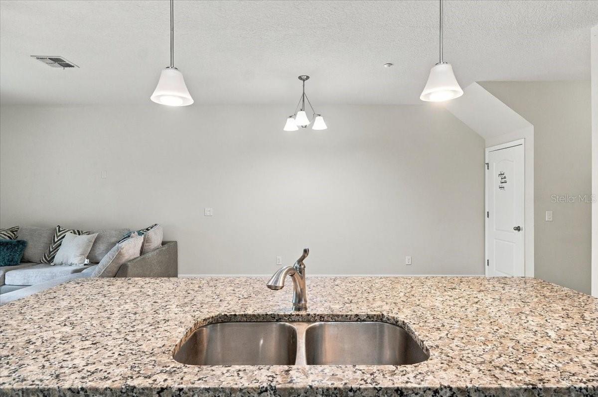 Granite kitchen island with double basin sink and stylish pendant lighting