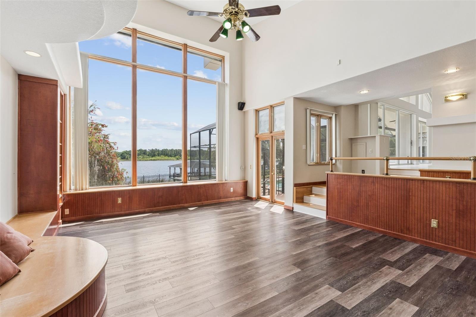 Sunken great room with soaring ceilings, lake-view windows, and French doors opening to the pool deck and lanai.