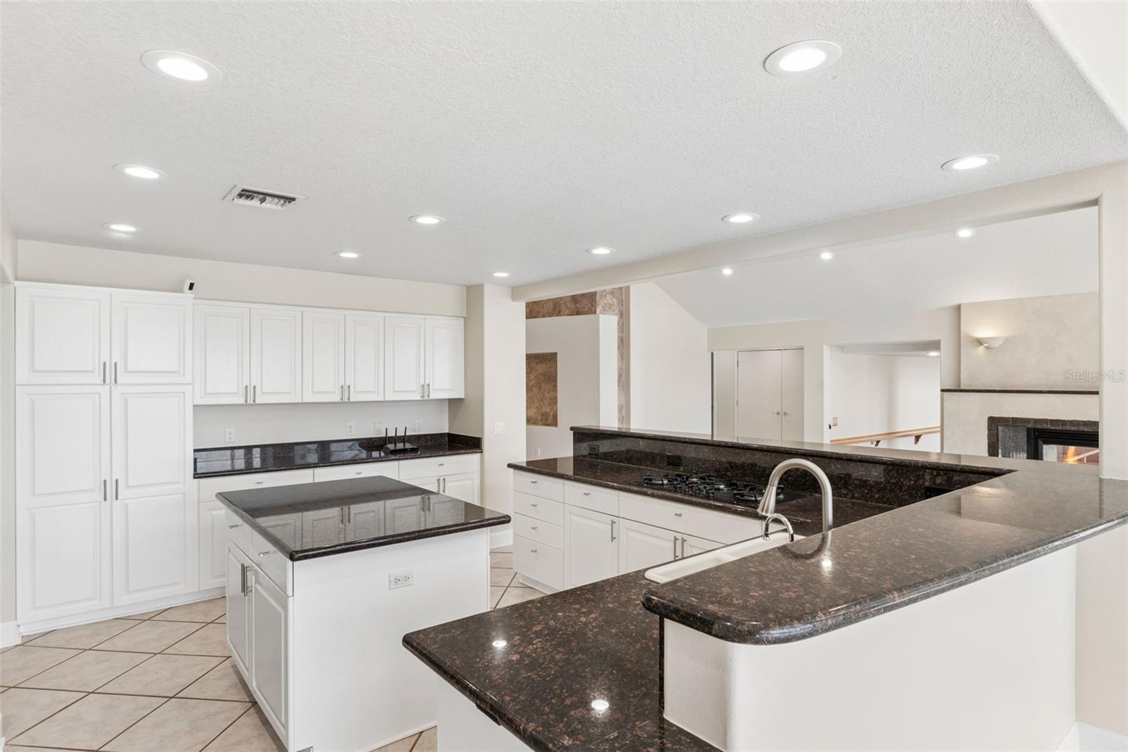 Spacious open kitchen with center island, abundant cabinetry, and views into the living room fireplace.