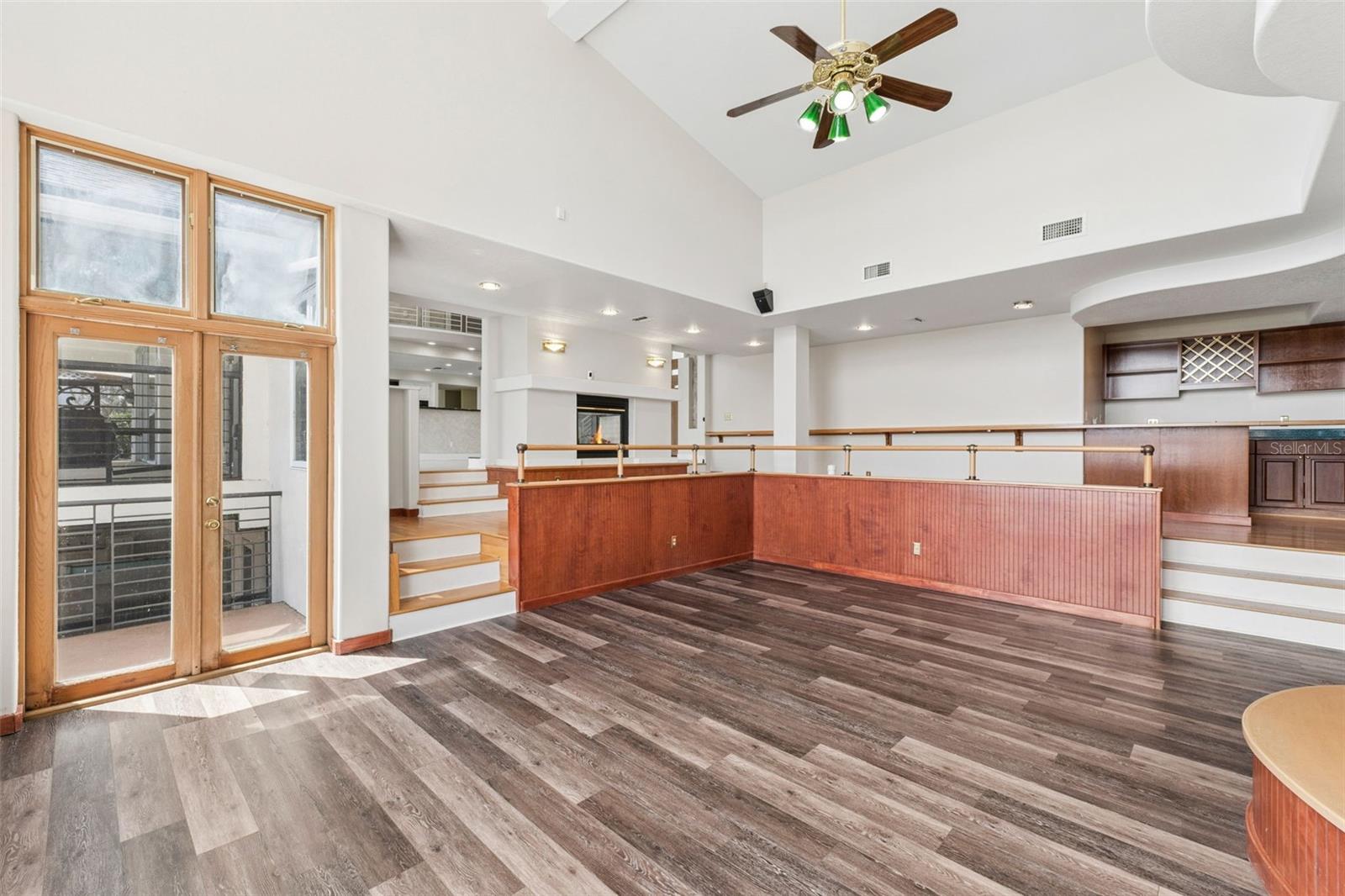 Sunken great room with soaring ceilings, lake-view windows, and French doors opening to the pool deck and lanai.