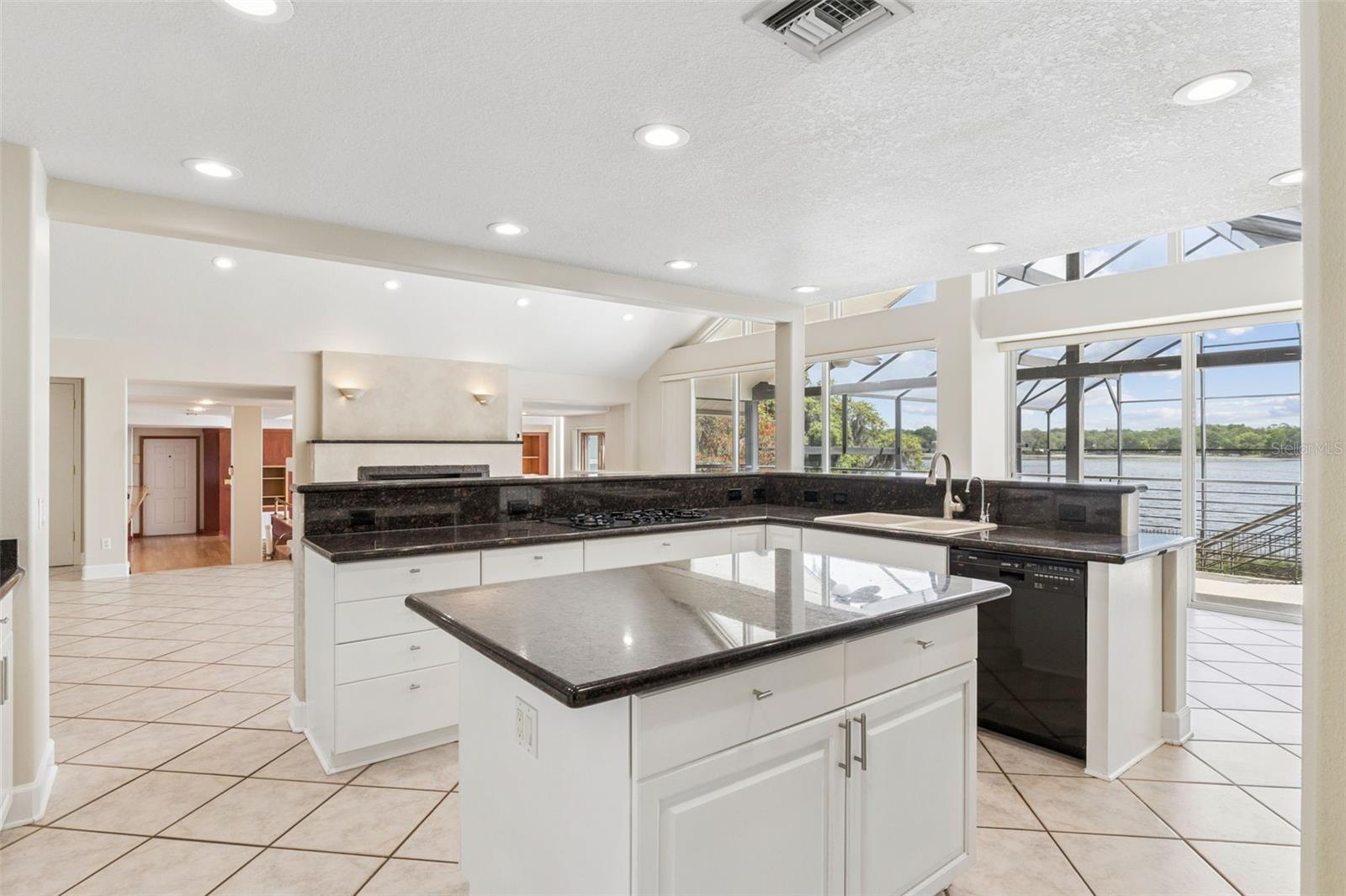 Open kitchen with center island overlooking the living room, sunken great room, and stunning lake views.