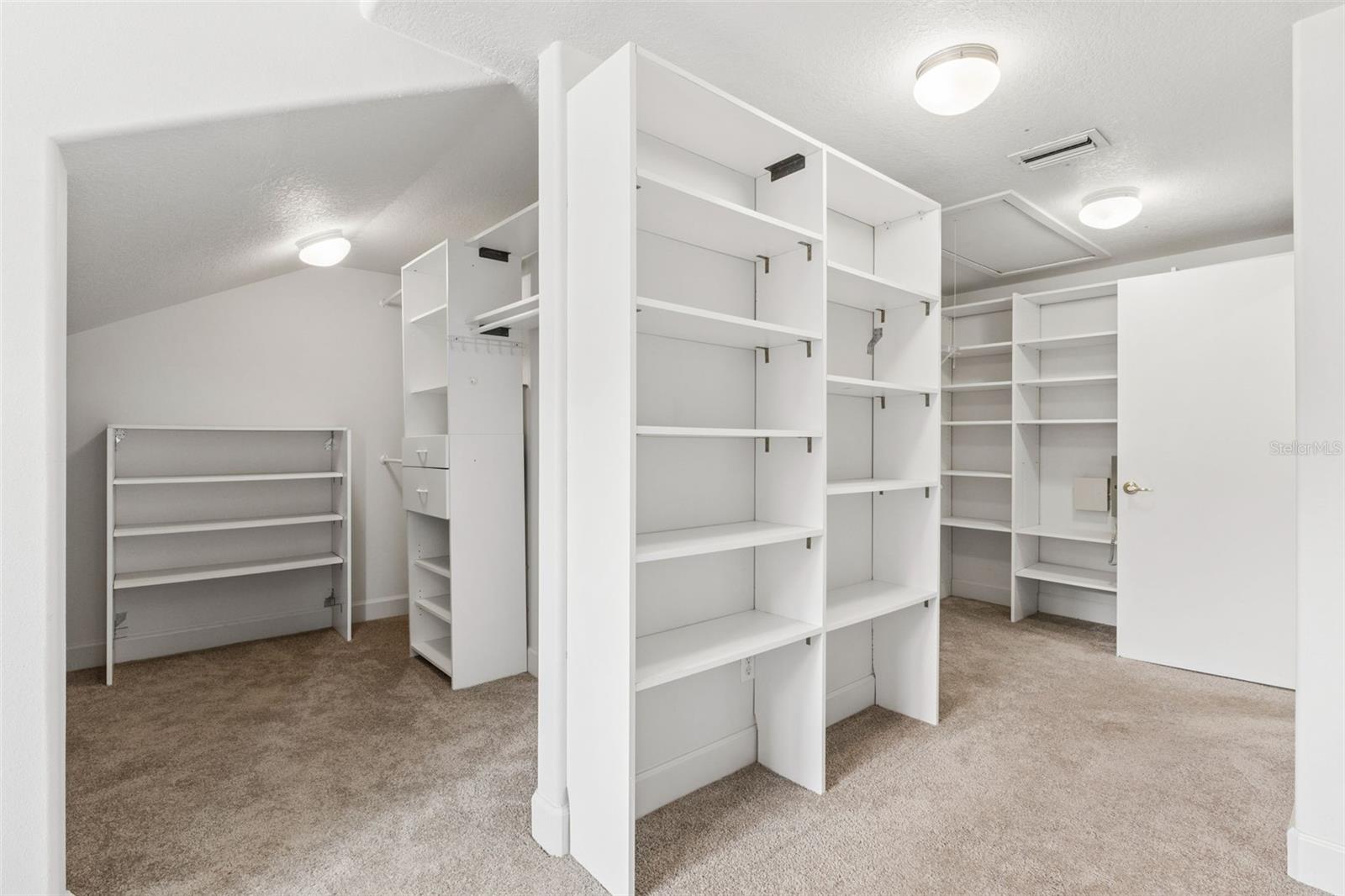 Massive walk-in closet with custom built-in shelving off the primary suite.