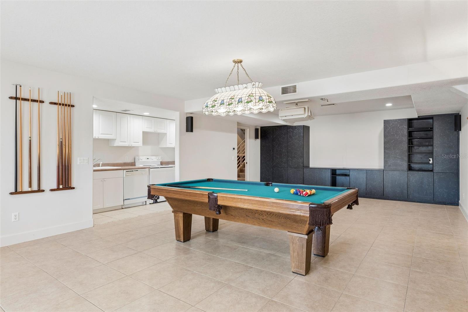 Full-size basement living room with kitchenette, offering separate living quarters with a bedroom and full bath leading to the pool deck.