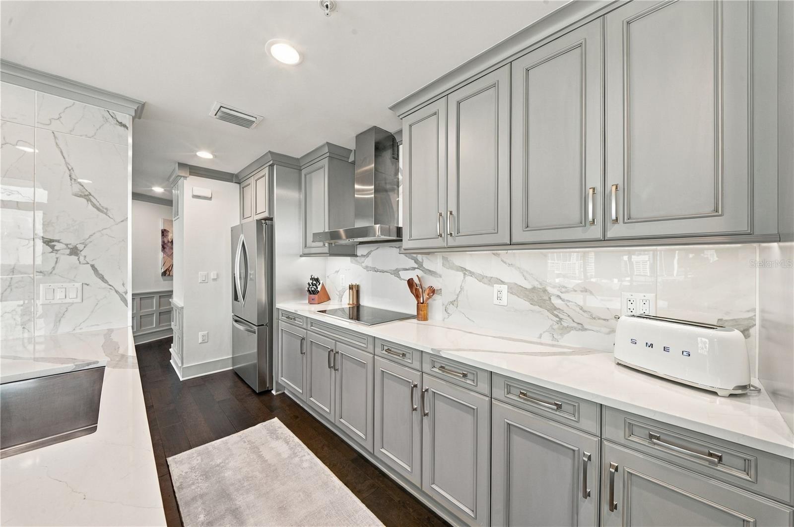 Kitchen | Quartzite countertops and full-height slab backsplash pair with streamlined cabinetry
