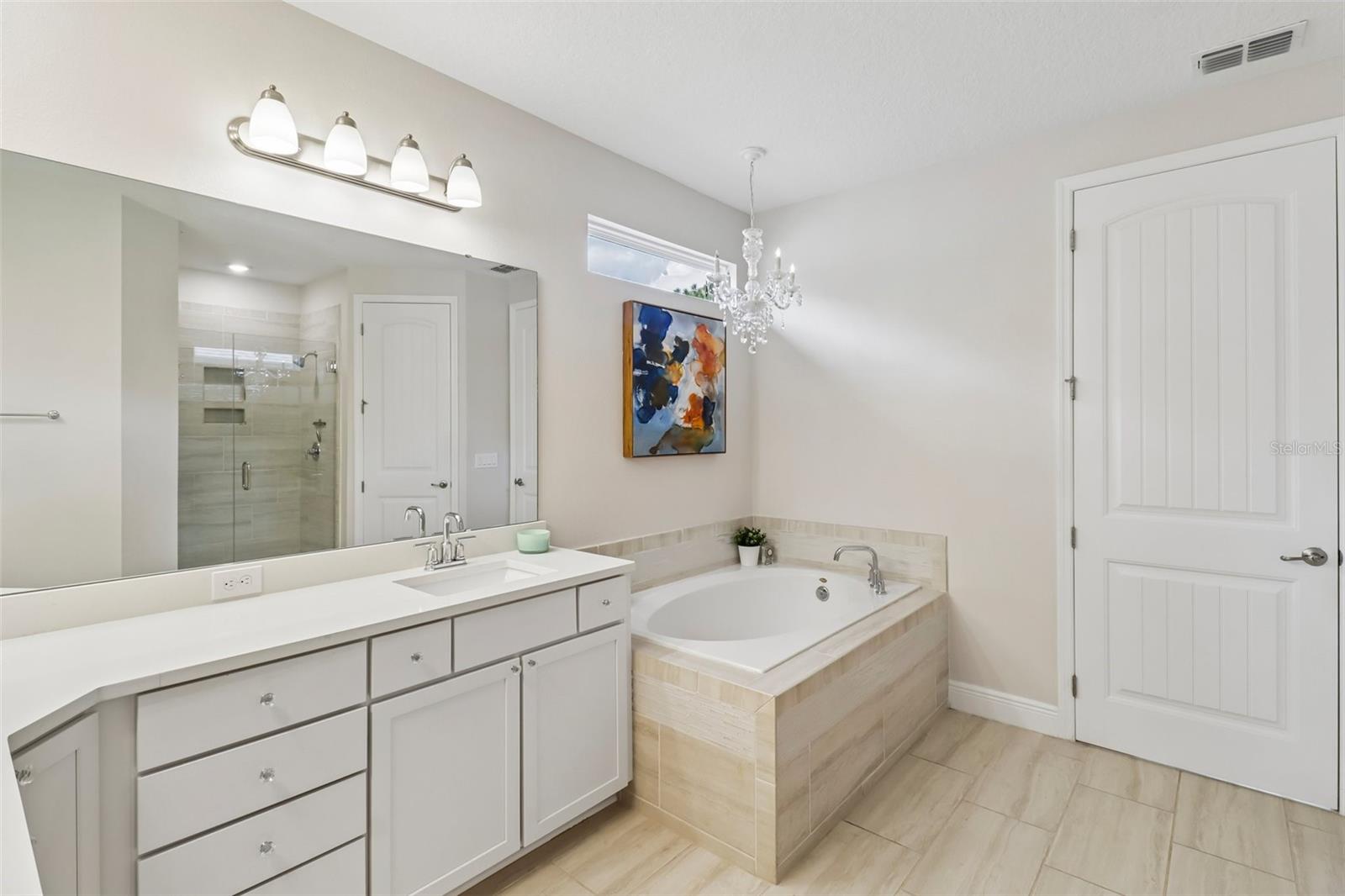 Upstairs primary bath with dual vanities, separate tub & glass enclosed shower