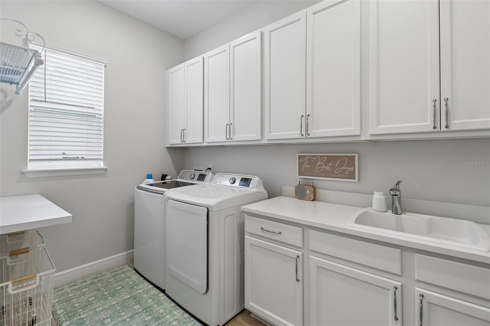Huge interior laundry room with a utility sink & extra cabinet & counter space
