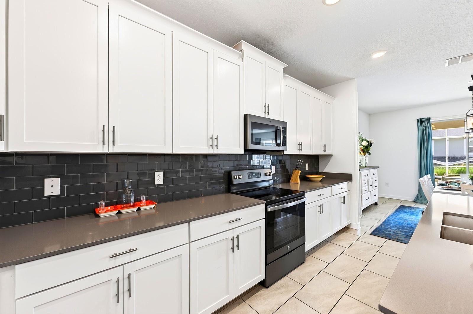 The spacious Kitchen is both stylish and functional, featuring 42-inch white cabinetry, QUARTZ COUNTERTOPS, a closet pantry, STAINLESS STEEL APPLIANCES and a sleek backsplash.