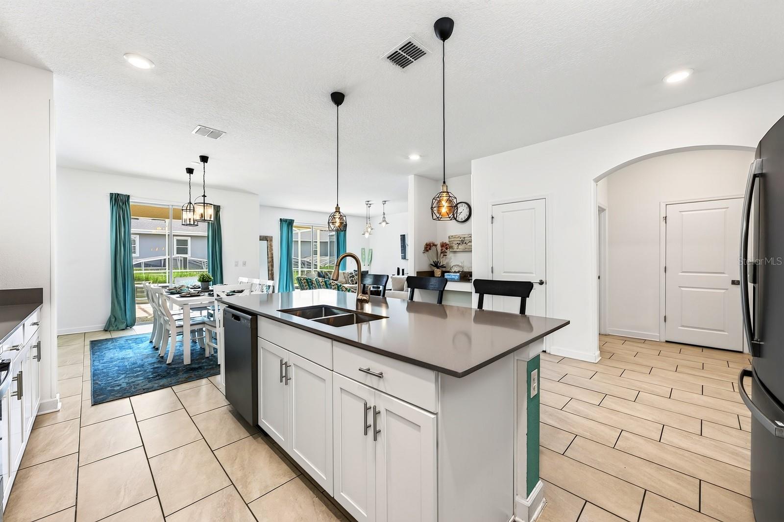 TWO SETS OF SLIDING GLASS DOORS bring in abundant natural light and create a seamless connection to the pool area, while CONTEMPORARY LIGHTING throughout adds a polished finishing touch.
