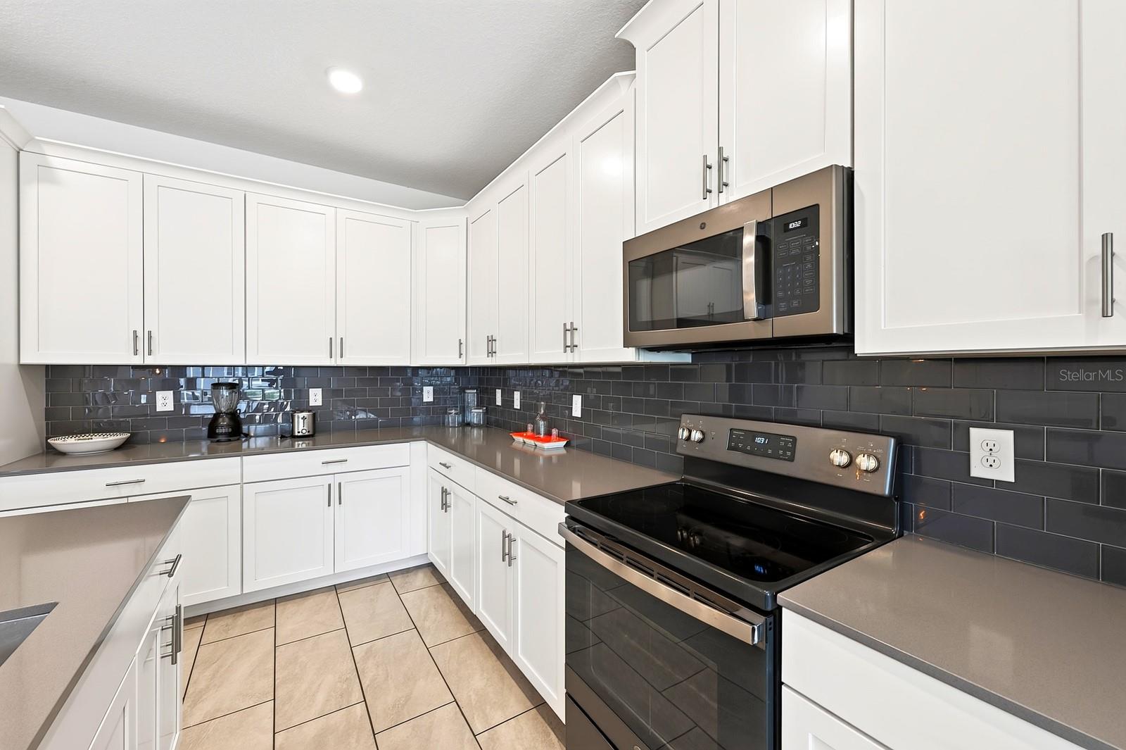 The spacious Kitchen is both stylish and functional, featuring 42-inch white cabinetry, QUARTZ COUNTERTOPS, a closet pantry, STAINLESS STEEL APPLIANCES and a sleek backsplash.