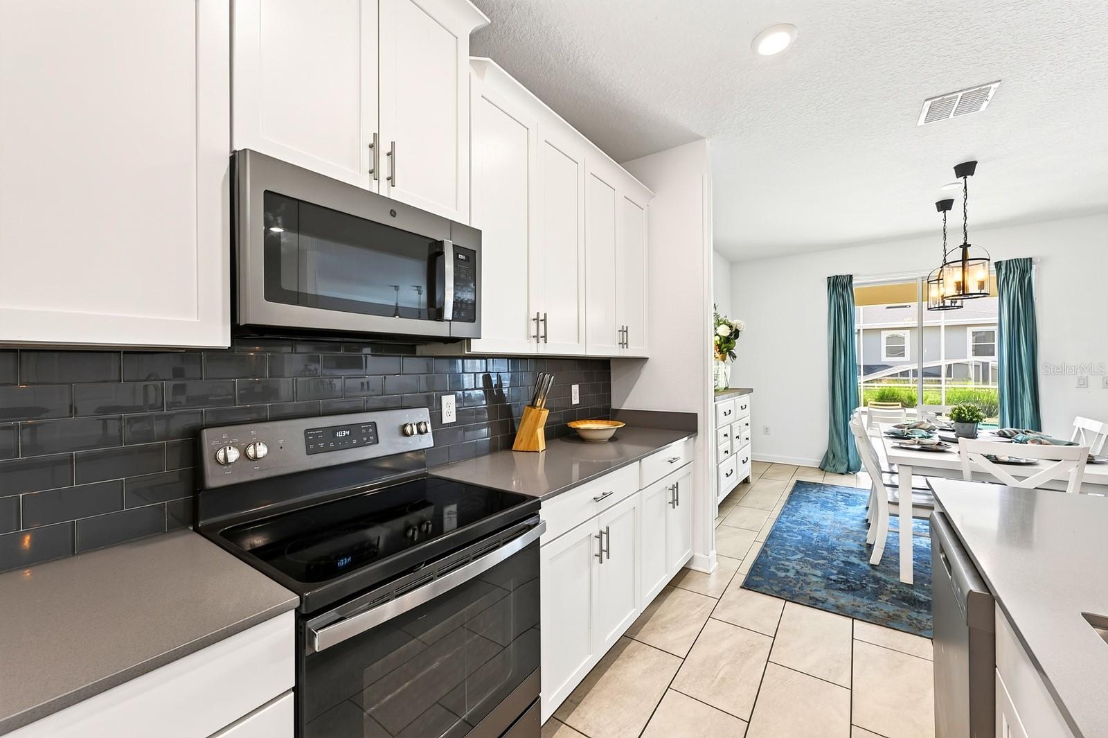 The spacious Kitchen is both stylish and functional, featuring 42-inch white cabinetry, QUARTZ COUNTERTOPS, a closet pantry, STAINLESS STEEL APPLIANCES and a sleek backsplash.