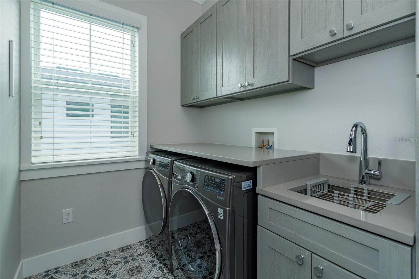 Second floor laundry room with utility sink and cabinetry