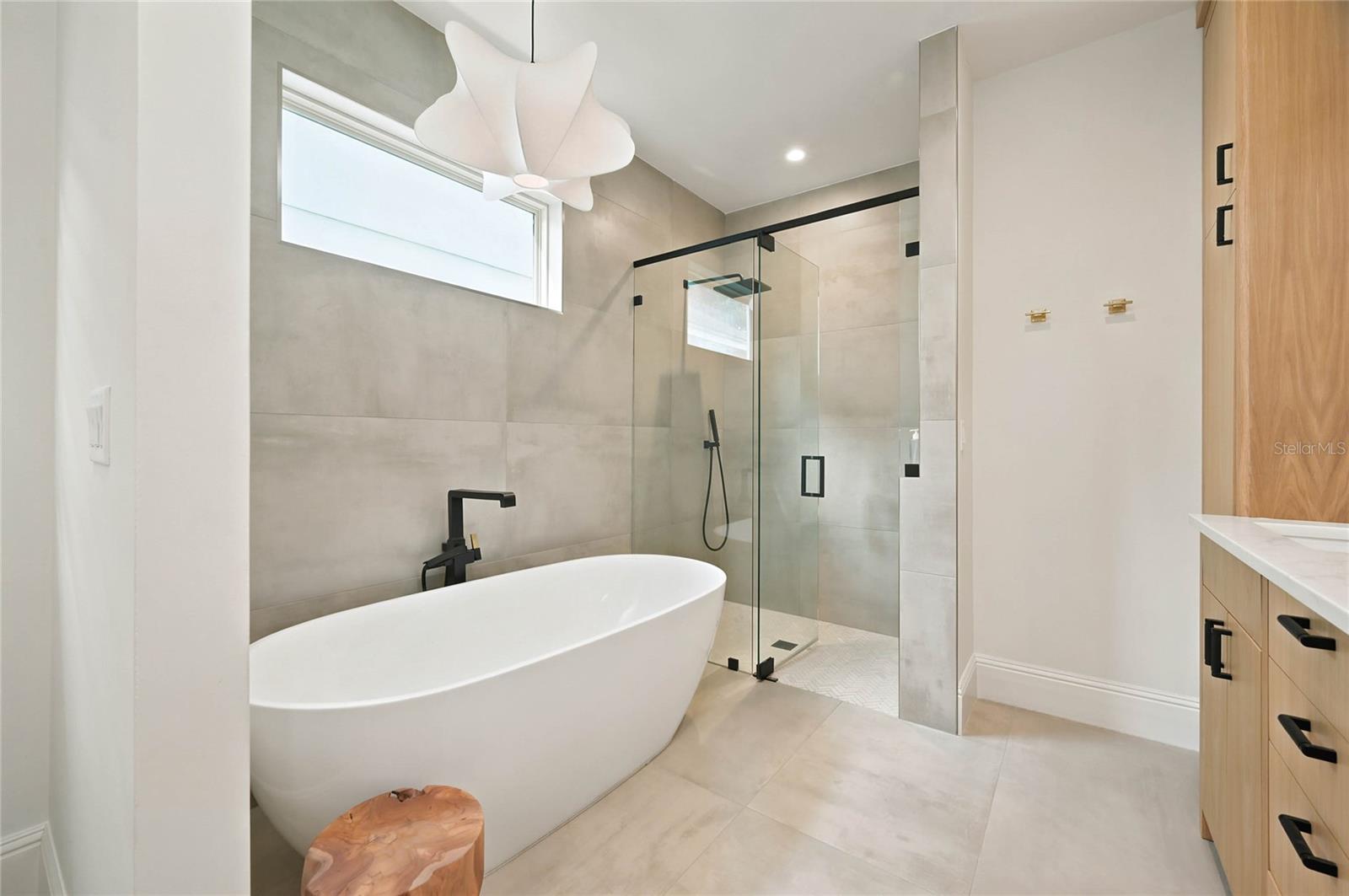 Sculptural soaking tub with bespoke lighting & oversized glass-enclosed shower with additional hand held wand and built in niche