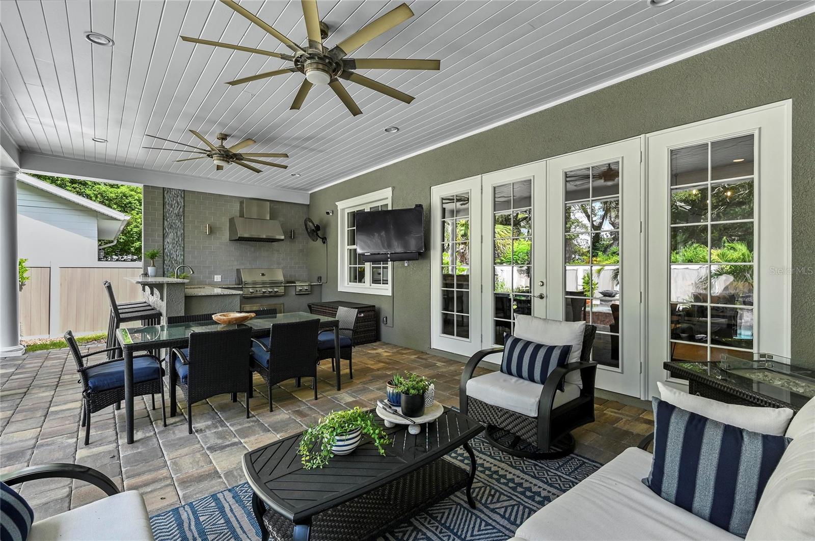 The back patio is a stunning living area providing room for seating, dining, cooking and entertaining, with the heavenly and lush landscape being reflected on all sides.