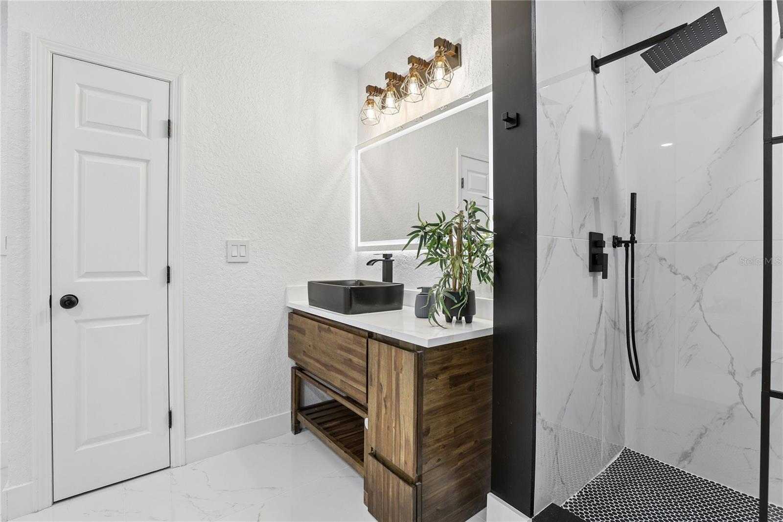 Designer primary bath with vessel sink, illuminated mirror and modern finishes