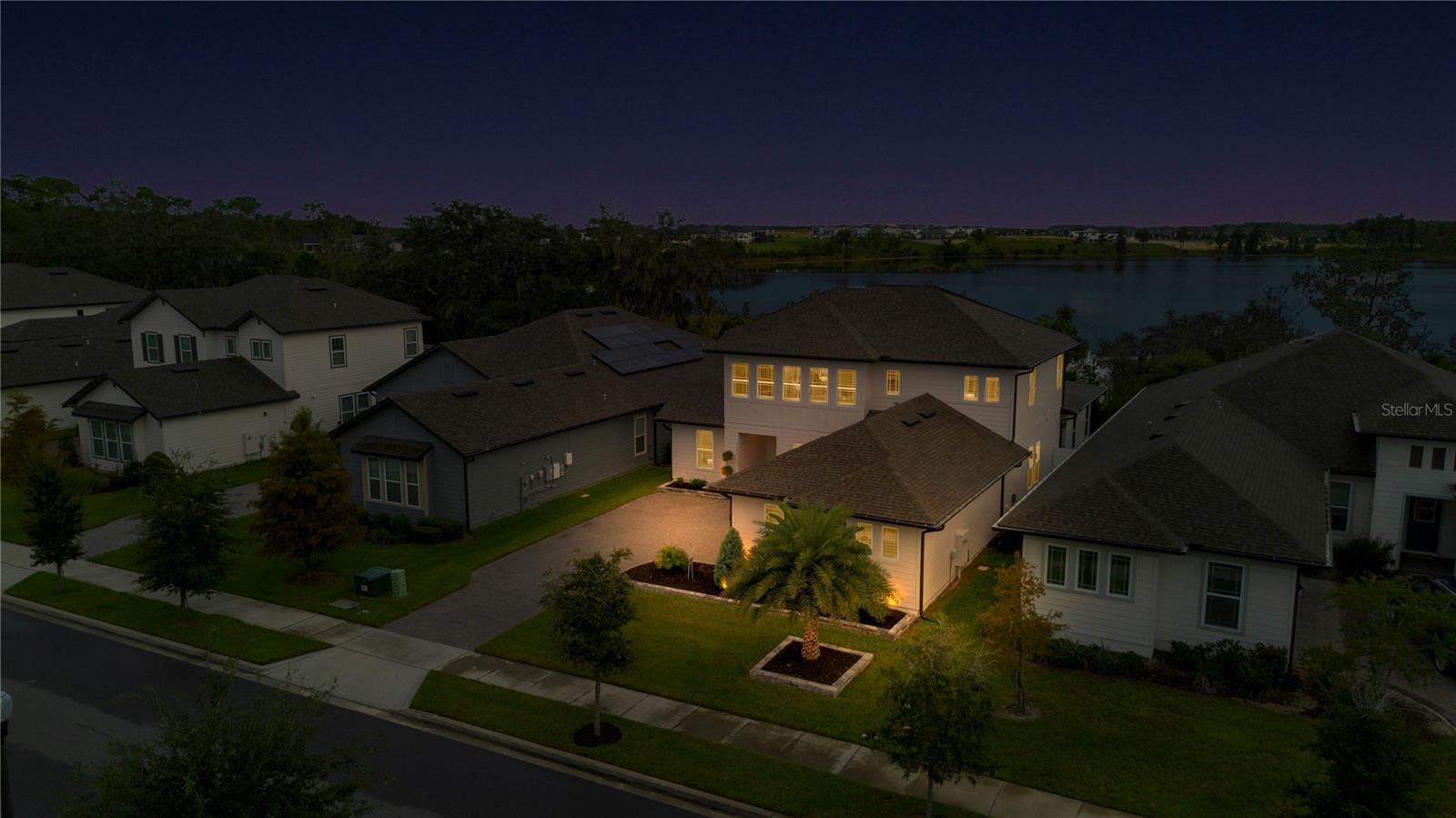 Angled twilight aerial highlights the homes exterior lighting and scenic surroundings.