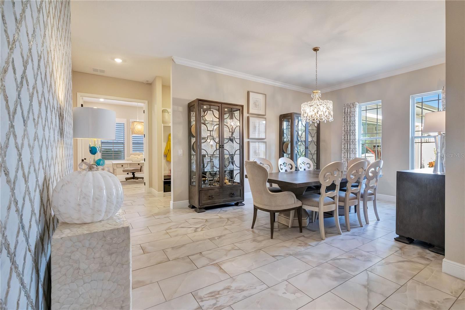 Elegant dining room featuring a statement chandelier, crown molding and upgraded tile flooring.