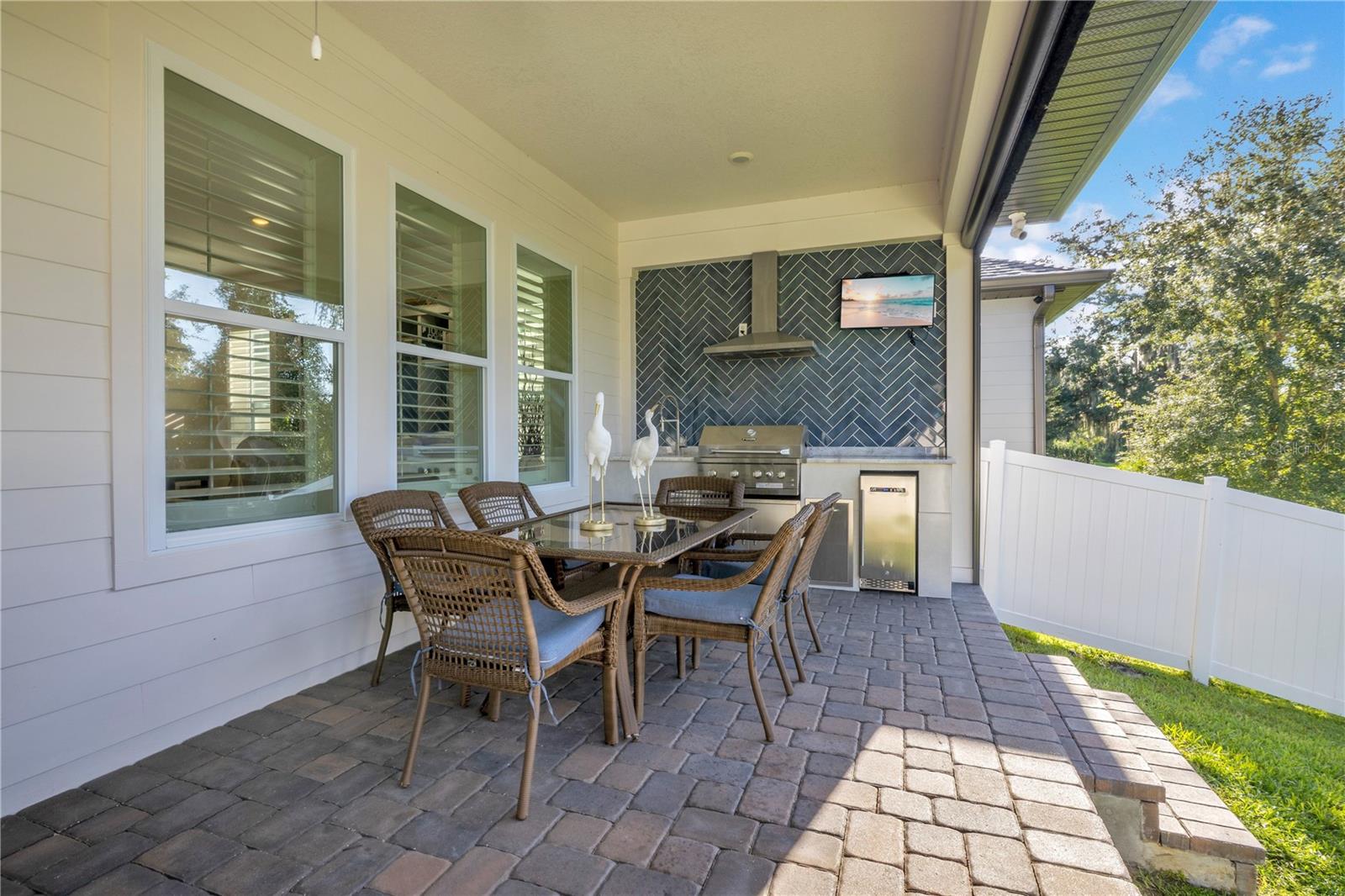 Covered outdoor dining area with a custom summer kitchen, built-in grill and beverage refrigerator.