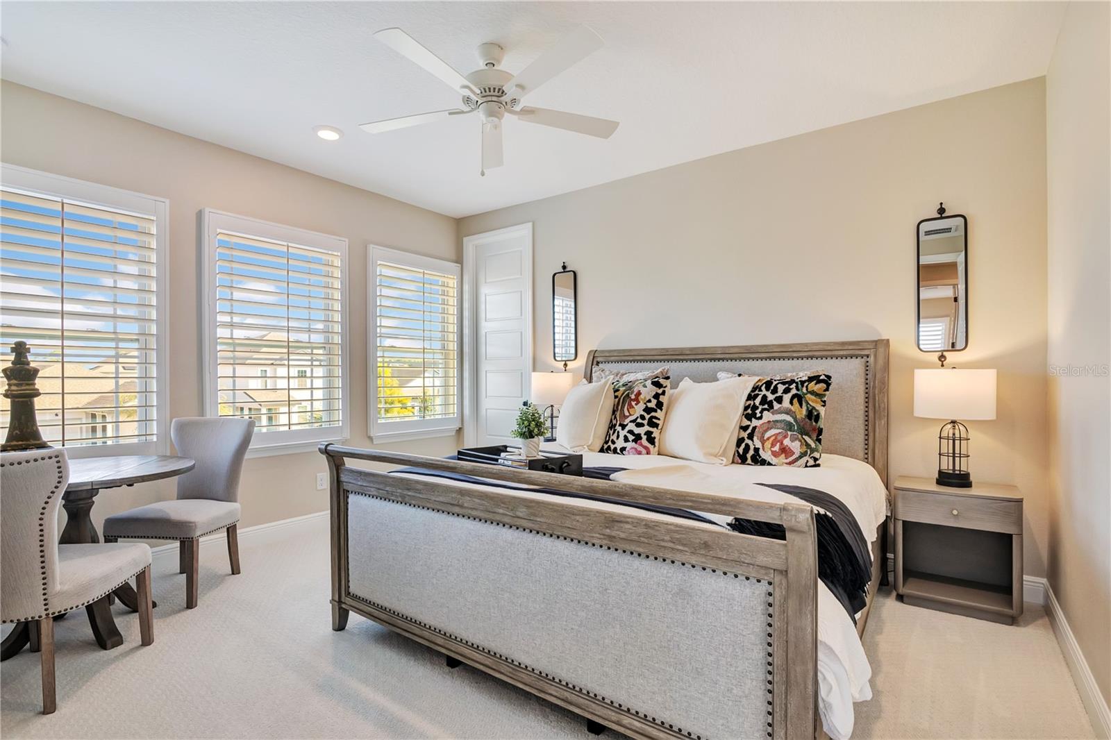 Inviting bedroom featuring plush carpet, plantation shutters and a ceiling fan.