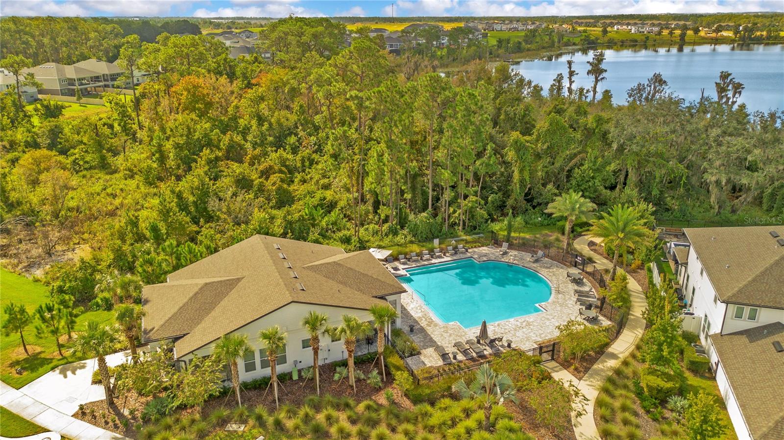 Community pool and clubhouse surrounded by landscaped grounds and mature trees.