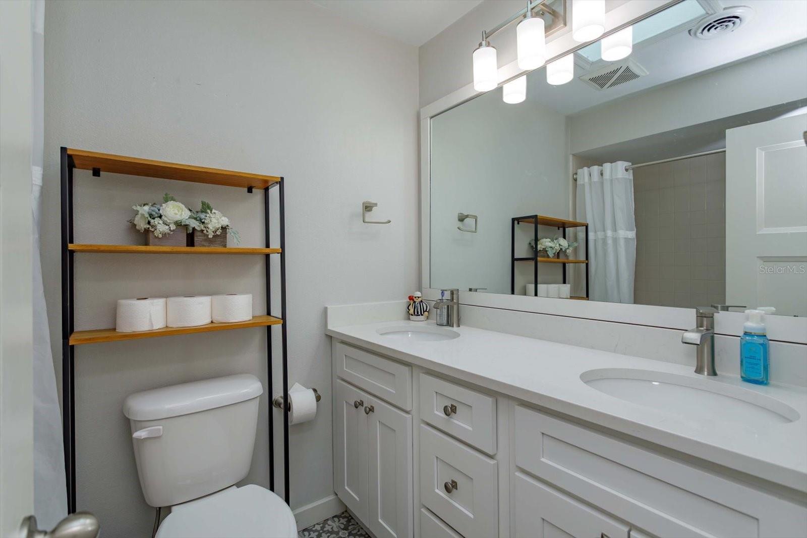 Updated hall bath with dual sinks, shaker cabinets, stone counters and updated fixtures
