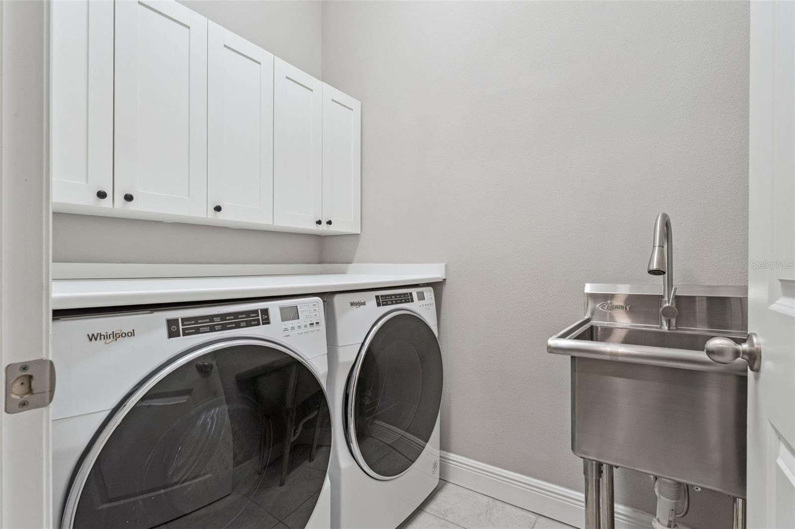 Convenient laundry room with upper cabinetry and space for full-size appliances.