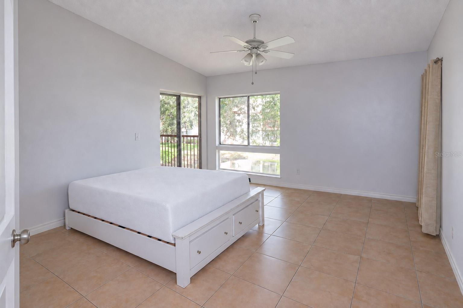 Bedroom 2 with pond view and slider access to balcony. One closet at right; a second one left of the entry door.