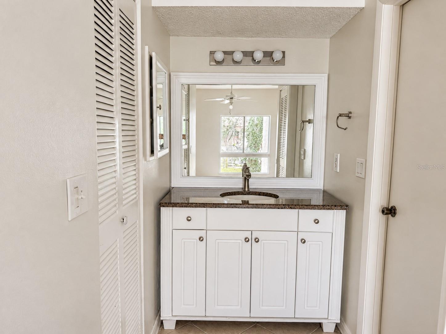 Updated primary vanity area; walk-in closet at left.  Shower and toilet area at right.