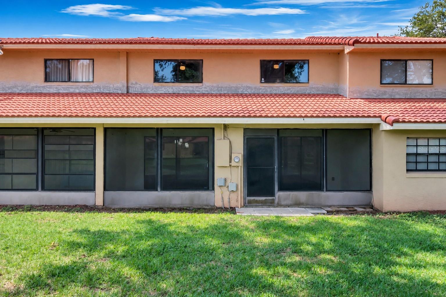 Screened lanai opens onto a shared green space.