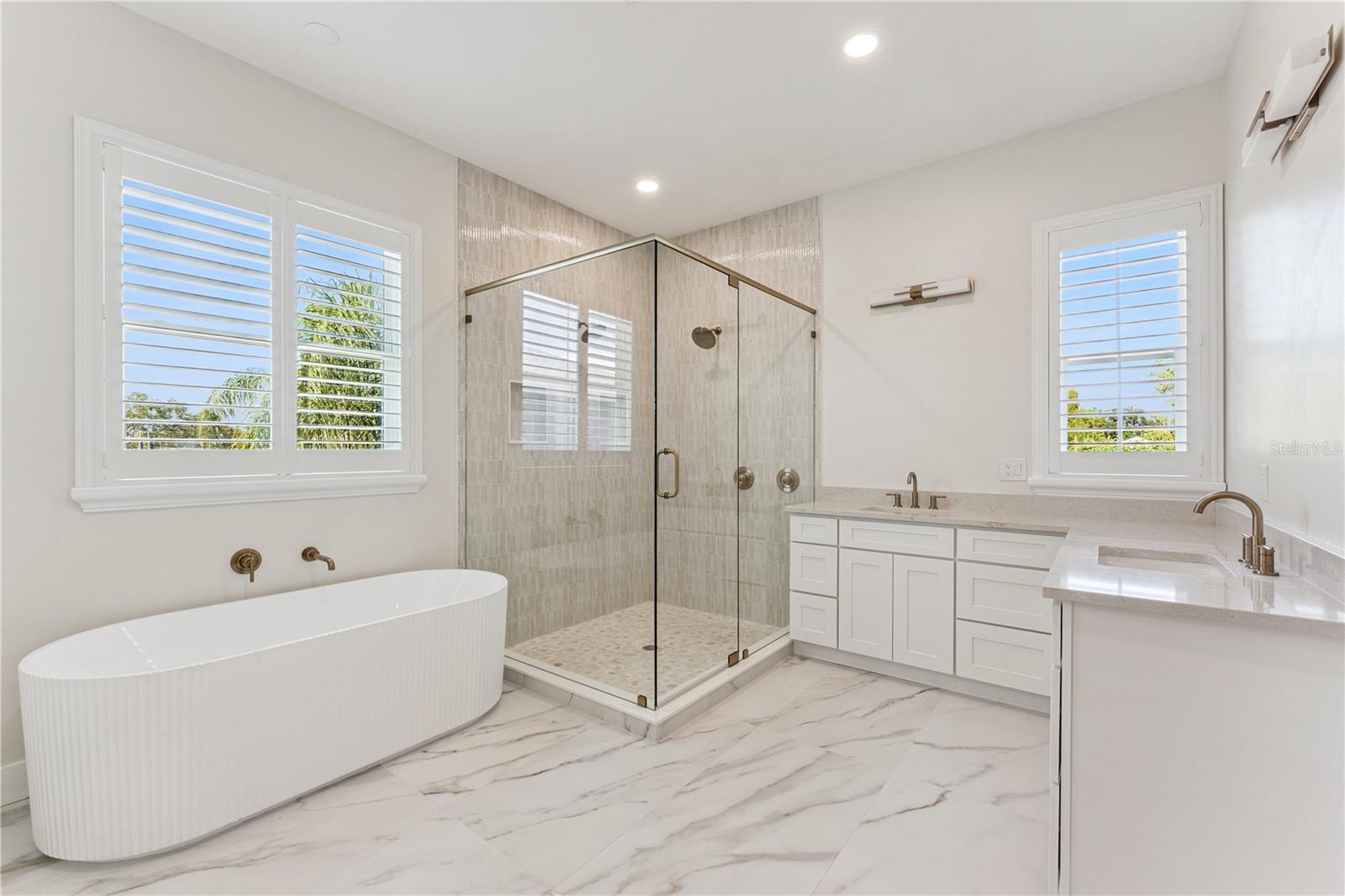 A freestanding tub, glass-enclosed shower, and two sinks define this spacious bathroom.